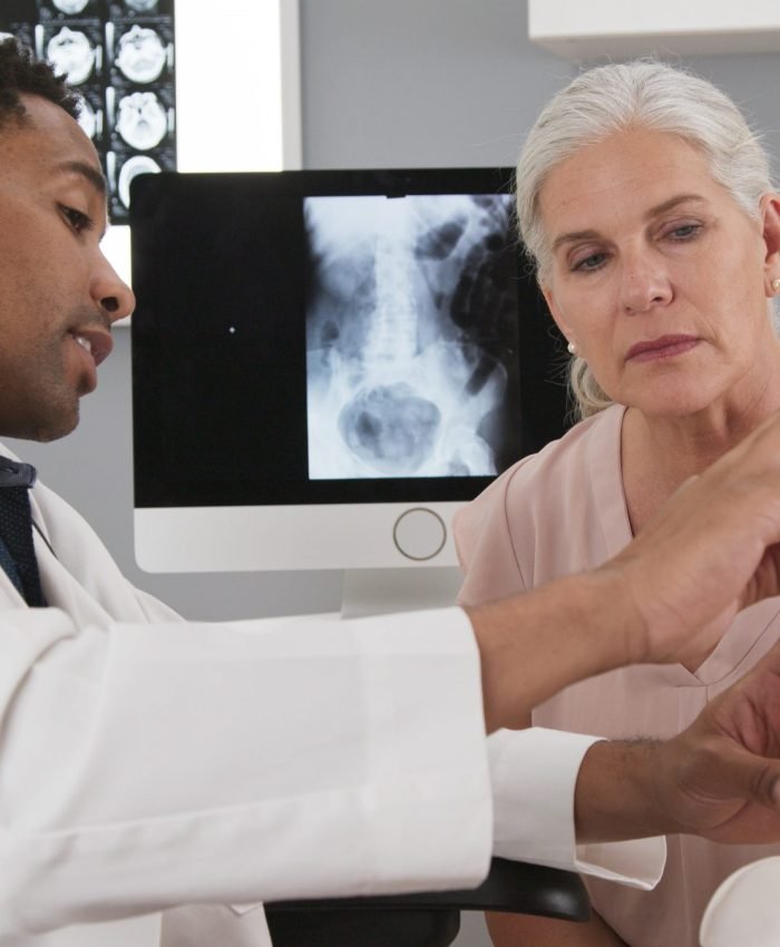 Senior female patient consulting with young doctor about back injury Senior female patient consulting with young doctor about back injury